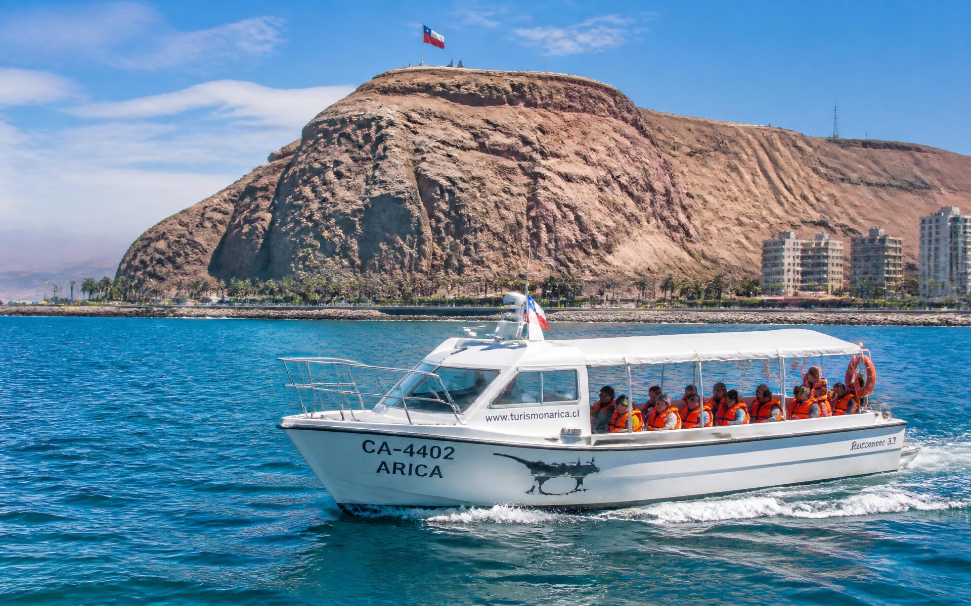 Lancha turística navegando frente a la costa de Arica