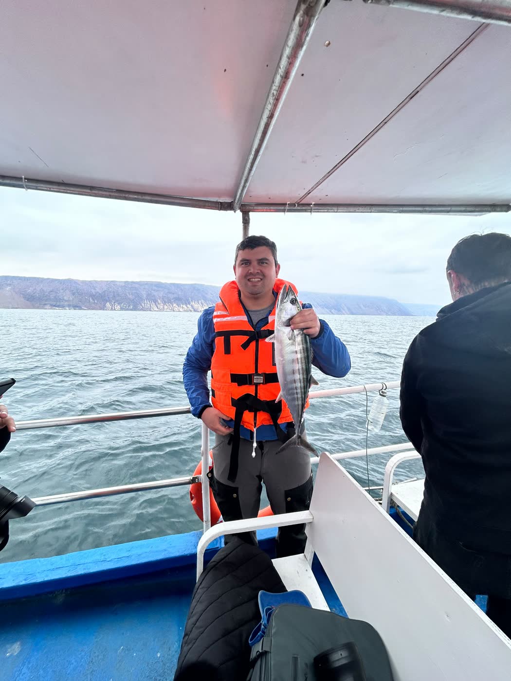 Pasajero mostrando un pescado recién capturado a bordo